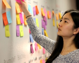 Student placing or moving post-it notes on a whiteboard