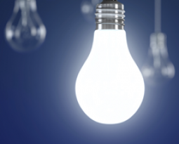 Several lightbulbs are hanging by strings -- only one of them is lit up.