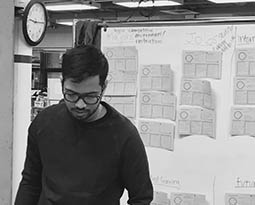 Student working in front of white board covered in sticky notes.